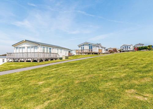 a row of houses on a grassy field next to a sidewalk at Meadow House Holiday Park in Amroth
