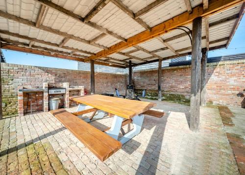 a patio with a wooden table in a brick building at Hill Farm Retreat in Wangford