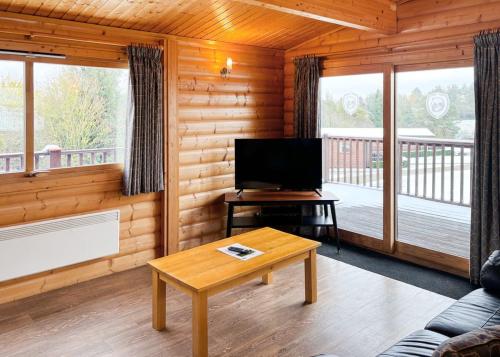 a living room with a flat screen tv in a log cabin at Rutland Lodges At Greetham Valley in Greetham