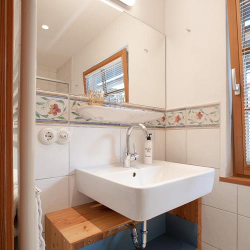a bathroom with a white sink and a mirror at Biohotel Gralhof in Weissensee