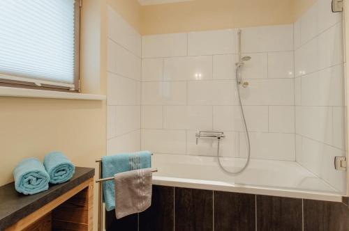 a bathroom with a tub and a shower with blue towels at Residenz Max mit eigenem Garten in Seefeld in Seefeld in Tirol