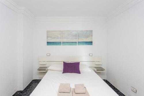 sypialnia z dużym białym łóżkiem z fioletową poduszką w obiekcie Lightbooking playa de Amadores La Concha w mieście Puerto Rico de Gran Canaria