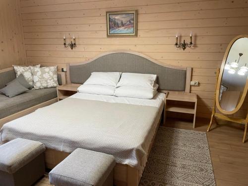 a bedroom with a bed and a couch and a mirror at Burger Trostyan Guest House in Slavske