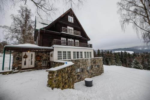 a large wooden house with snow on the ground at Aparthotel Panorama in Deštné v Orlických horách