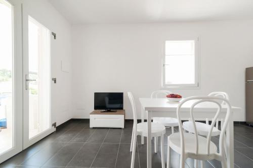 a white dining room with a white table and chairs at Salentipity in Marina di Pescoluse
