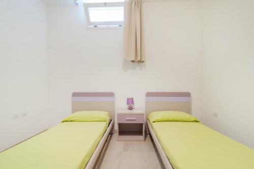 a room with two beds and a desk and a window at Salentipity in Marina di Pescoluse