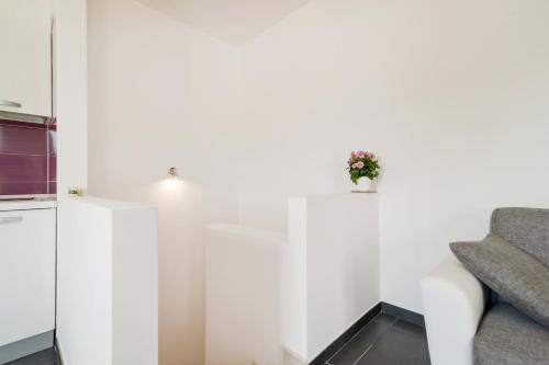 a white living room with a couch and a plant at Salentipity in Marina di Pescoluse