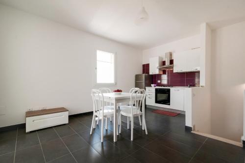 a kitchen with white cabinets and a table and chairs at Salentipity in Marina di Pescoluse