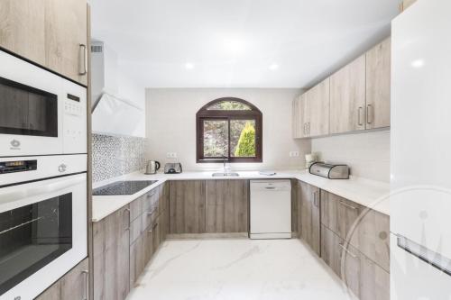 eine Küche mit Holzschränken und einem Fenster in der Unterkunft La Manga Club - Los Altos 367 in Atamaría