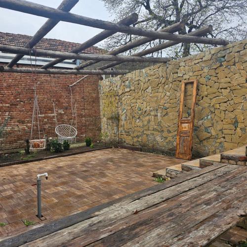 a patio with a stone wall and a wooden door at Niabi 3BDR Villa with pool in Tbilisi City