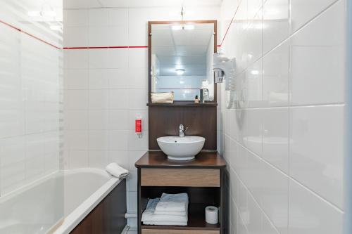 a white bathroom with a sink and a bath tub at Appart'City Confort Agen Centre in Agen