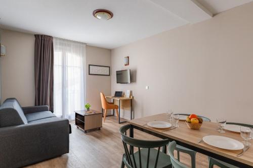a living room with a couch and a table with chairs at Appart'City Confort Agen Centre in Agen