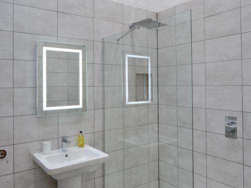 a bathroom with a sink and a shower with two mirrors at The Hemmel in Greenhaugh