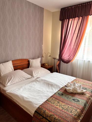 a bedroom with a large white bed with a window at Hotel Erzsébet in Hévíz