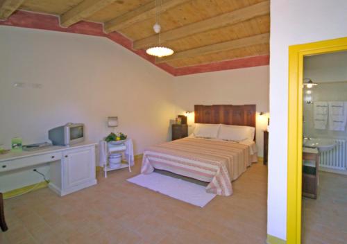 a bedroom with a bed and a desk and a tv at Sa Crescia Ezza in Berchiddeddu