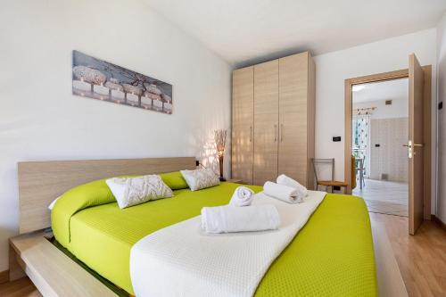 a bedroom with a green and white bed with towels on it at Agritur Laura in Nago-Torbole