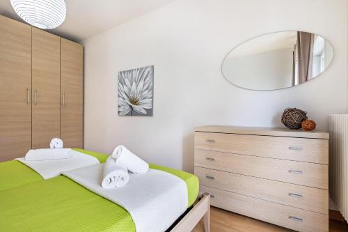 a bedroom with a green and white bed and a mirror at Agritur Laura in Nago-Torbole