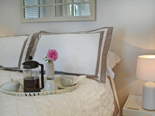 a tray with tea sets and a flower on a bed at Petit Knowle in Cuckfield