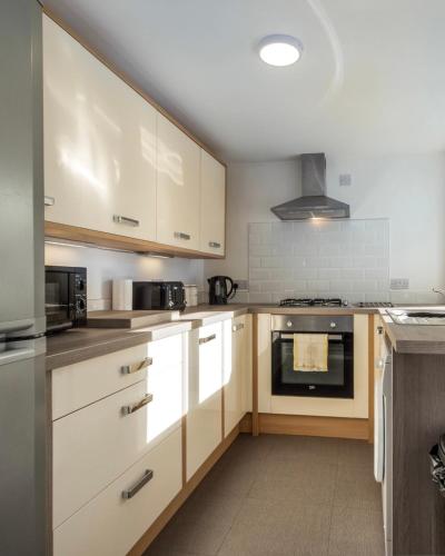 a kitchen with white cabinets and a stove at Apex Living NE - Beachville House 4 Beds FREE PARKING in Sunderland