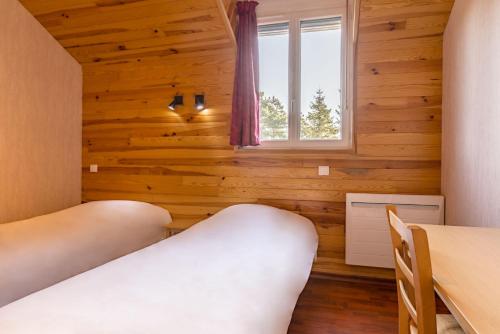 a bedroom with wooden walls and a window and two beds at Azureva Murol in Murol
