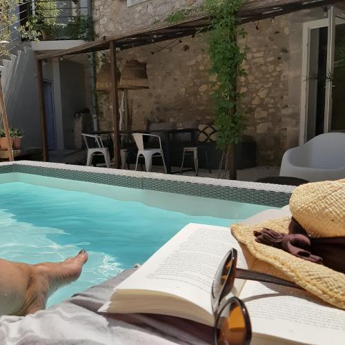 une personne posant dans une piscine avec un livre et des lunettes dans l'établissement Maison Mymoodz, à Cornillon