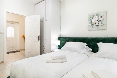 a white bedroom with a green headboard and two white beds at Villa Irene Royale - Pool - Sea View - Free Cruise in Tigaki