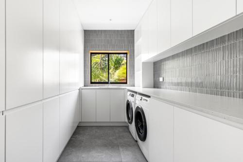 a laundry room with two washers and a window at Ourie Place 200m to Werri Beach in Gerringong