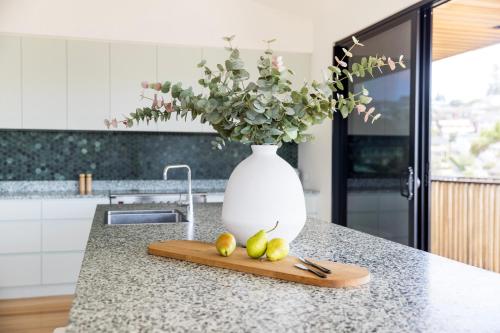 a white vase with a bouquet of flowers in a kitchen at Ourie Place 200m to Werri Beach in Gerringong