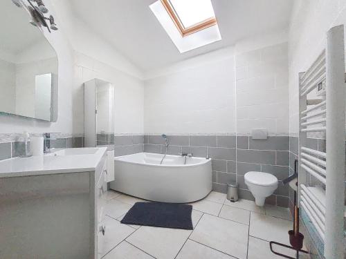 La salle de bains blanche est pourvue d'une baignoire et de toilettes. dans l'établissement Le 34 degrés sud - 2 chambres - jardinet et jacuzzi, à Thèzan-lès-Béziers