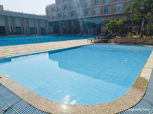 a large blue swimming pool in front of a building at Ramada by Wyndham Ahmedabad Narendra Modi Stadium Motera in Ahmedabad