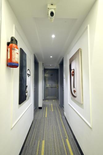 a hallway with a door and paintings on the walls at MyOtel - Santacruz in Mumbai