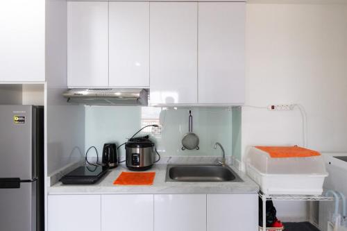 a small kitchen with white cabinets and a sink at Spacious 2 Bedroom Apartment Near SMS Mall in Pumpangsineng