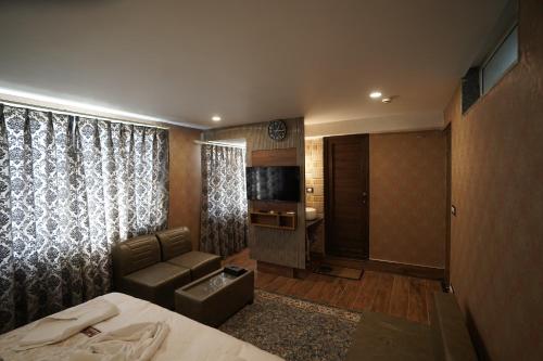 a hotel room with a bed and a couch and a television at Hotel Asian Comfort in Srinagar