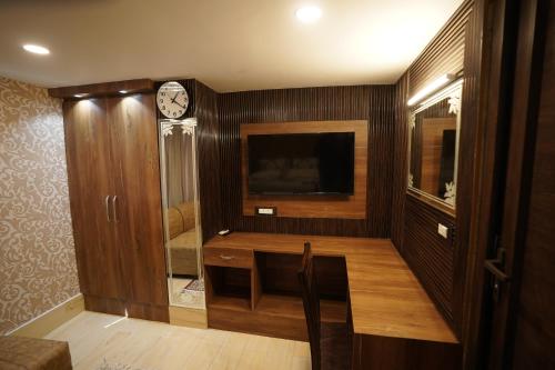 a room with a tv and a clock on a wall at Hotel Asian Comfort in Srinagar
