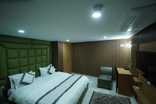 a bedroom with a bed and a desk and a television at Hotel Asian Comfort in Srinagar