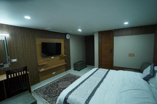 a bedroom with a large bed and a television at Hotel Asian Comfort in Srinagar