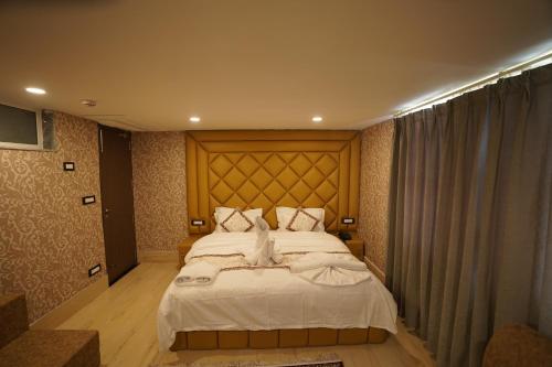 a bedroom with a large bed with a wooden headboard at Hotel Asian Comfort in Srinagar