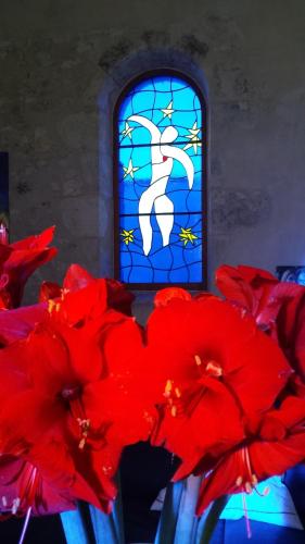 un vase avec des fleurs rouges devant un vitrail dans l'établissement La Chapelle - Private Heated Pool, Village Centre, à Loubès-Bernac
