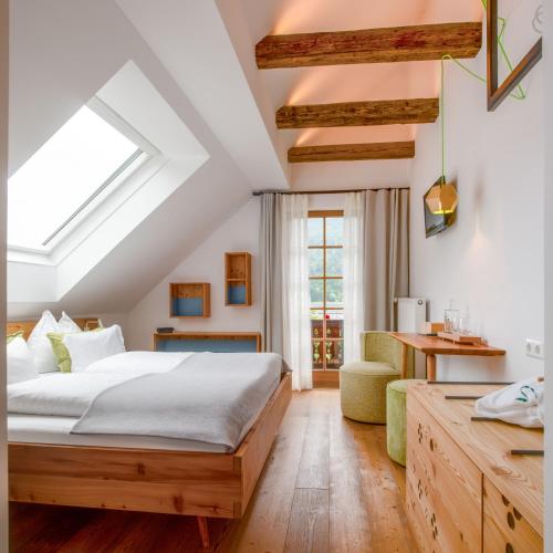 a bedroom with a bed and a couch and a window at Biohotel Gralhof in Weissensee