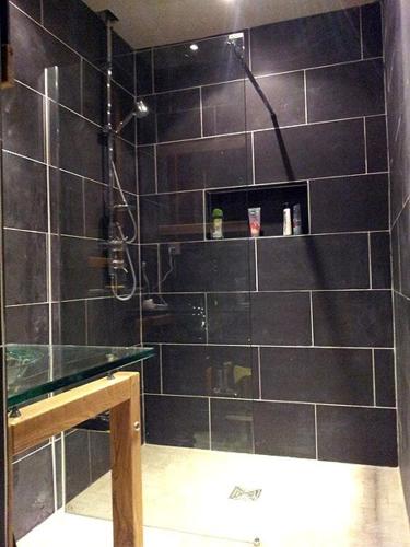 La salle de bains est pourvue d'une douche et de murs en carrelage noir. dans l'établissement La Chapelle - Private Heated Pool, Village Centre, à Loubès-Bernac