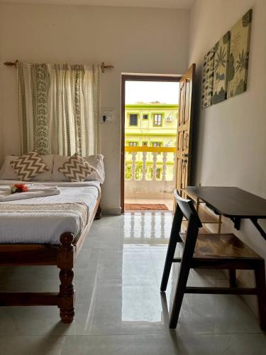 a bedroom with a bed and a desk and a window at Evaddo Homes in Goa