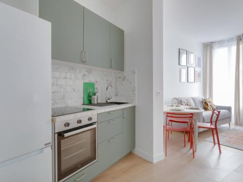 une cuisine avec des placards blancs et une table avec une chaise dans l'établissement La Pause Citadine, à Saint-Denis