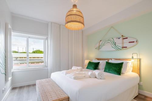 una camera da letto con un letto bianco con una tavola da surf sul muro di Yellow Breeze Apartament a Viana do Castelo