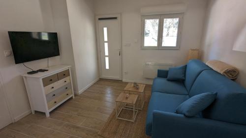a living room with a blue couch and a flat screen tv at Studio cosy neuf calme -Parking Terrasse privée Piscine 5mn Gare TGV Aix et ZA Aix la Duranne 15 mn Aéroport Marseille in Cabriès