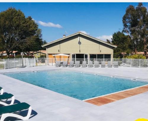 une piscine avec des chaises et un bâtiment dans l'établissement Coin de Paradis Lac et ocean Sans vis à vis, à Hourtin