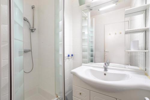a white bathroom with a sink and a shower at Appartement Cosy Le Phoebus in Canet-en-Roussillon