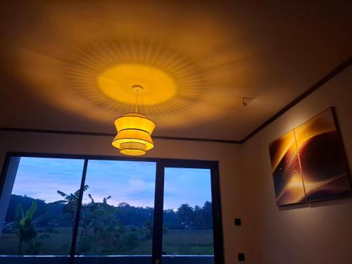a light hanging from a ceiling in a room with a window at Mini Ricefilds rooms in Batukaras