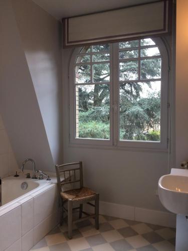 une salle de bain avec une baignoire, une chaise et une fenêtre dans l'établissement House facing Roland Garros stadium - 5 bedrooms, à Boulogne-Billancourt