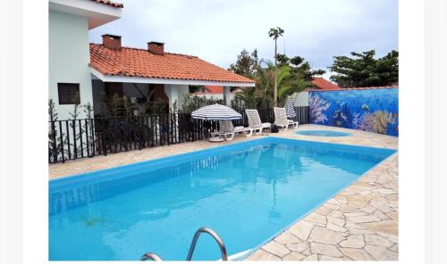 a swimming pool in front of a house at Colônia de Férias Beleza e Arte in Caraguatatuba