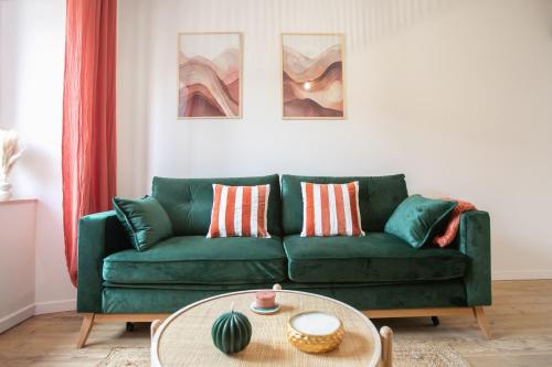 a living room with a green couch and a table at Bel appartement neuf en plein centre in Brantôme